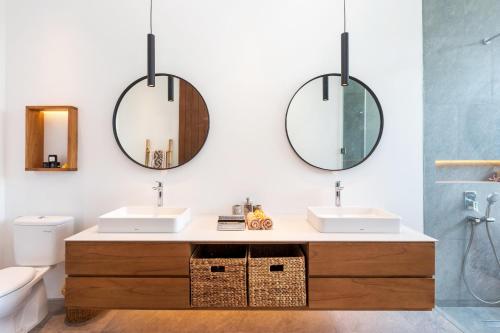 a bathroom with two sinks and two mirrors at Botanika Estate 3 BR Private Pool Villa - 15 mins to the beach in Canggu