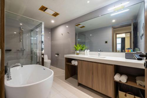a bathroom with a tub and a large mirror at Citadines Zhengda Mall Hefei in Hefei