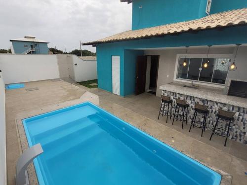 a blue swimming pool in front of a house at Casa de Praia - Búzios in Búzios