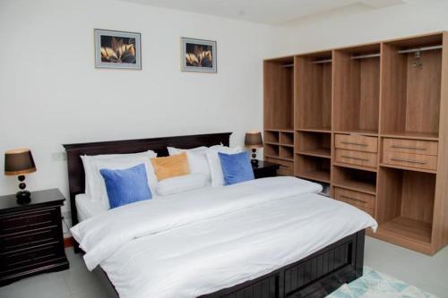 a bedroom with a large bed and wooden cabinets at Brand New Condo Apartment in Kampala