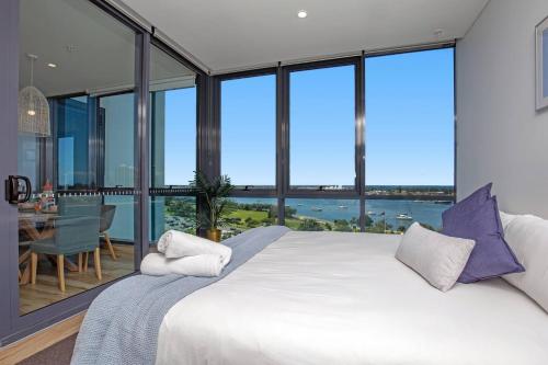 a bedroom with a large bed and large windows at Como Prestige Breathtaking Southport Sundale in Gold Coast