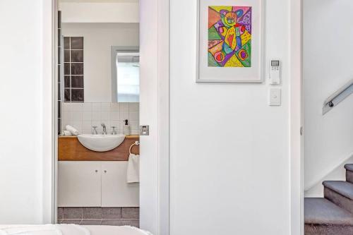 La salle de bains est pourvue d'un lavabo et d'un miroir. dans l'établissement Stellar - Spacious Rooftop Dreamscape in Adelaide, à Rose Park