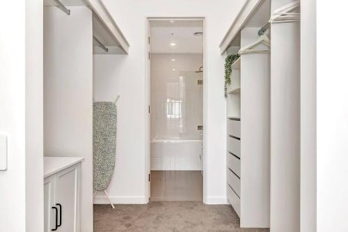 a bathroom with a walk in closet with white cabinets at 'The Outlook' Light-filled Nordic Contemporary in Glenunga