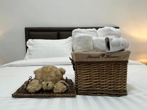 a basket of towels and a teddy bear on a bed at DM Hotel & Cafe in Ban Na Tho
