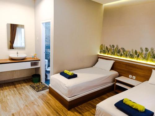 Pokój hotelowy z 2 łóżkami i umywalką w obiekcie Caniga Hotel Yogyakarta w mieście Gondowulung