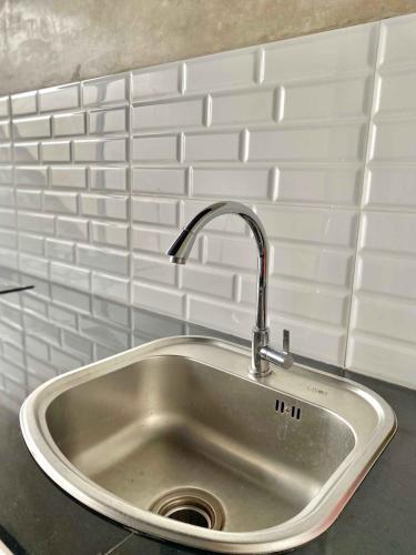 a stainless steel sink in a kitchen with white tiles at Sampai Villa Ruang Tepi in Yogyakarta