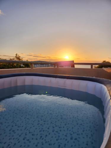 a swimming pool with a sunset in the background at Cozy pavillon with private jacuzzi on rooftop terrace - Jolly's Rock in Grand Gaube