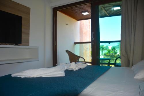 1 dormitorio con 1 cama y vistas a un balcón en Na praia - Araça 407 Luxo - Lateral vista mar, en Natal