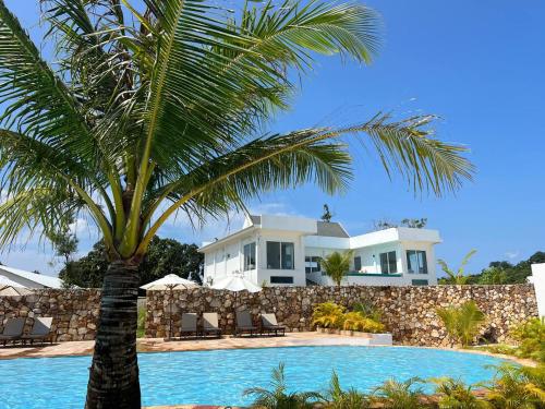 a palm tree in front of a house with a swimming pool at You&Me Resort in Koh Rong Island