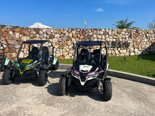 two atvs and a golf cart parked next to a stone wall at You&Me Resort in Koh Rong Island