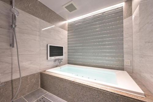 uma casa de banho com uma banheira, uma televisão e um chuveiro em Hotel Pasadena レジャーホテル em Nagoya