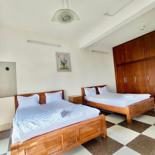 um quarto com 2 camas e um piso em xadrez em Hoàng Nam - 617 Nguyễn Thị Định, Q2 - by Bay Hostel em Ho Chi Minh