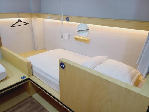 Una pequeña habitación con una cama y un espejo. en Elephant Hostel Nampo, en Busan