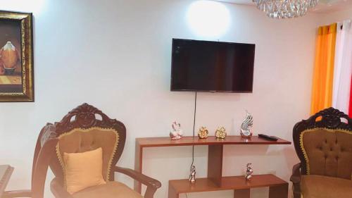 ein Wohnzimmer mit 2 Stühlen und einem Tisch mit einem TV in der Unterkunft Cómodo apartamento en Santiago in Licey al Medio