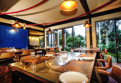 uma sala de jantar com mesas, cadeiras e janelas em Hotel Bulwark em Nuwara Eliya
