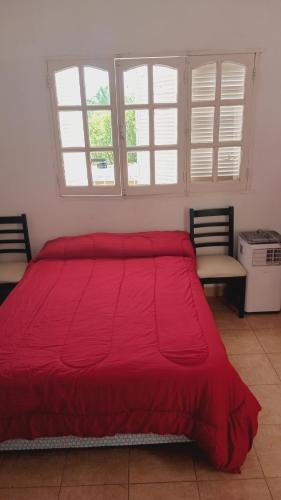 a large red bed in a room with two windows at Alquiler temporario Catamarca in San Fernando del Valle de Catamarca