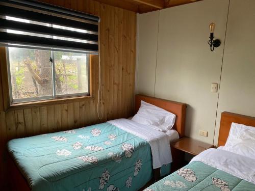 2 camas en una habitación con ventana y 1 cama sidx sidx sidx sidx en Cabaña Paso de los toros en San Fabián de Alico