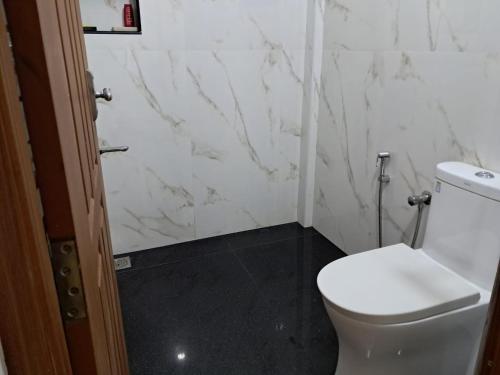 La salle de bains est pourvue de toilettes blanches et de murs en marbre. dans l'établissement Megapodenesthomestay, à Parūr