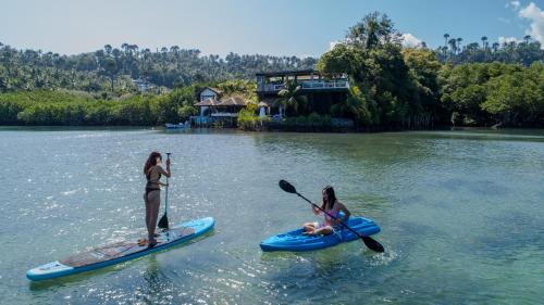 two girls are on paddle boards in the water at Edgewater Dive & Spa Resort in Puerto Galera
