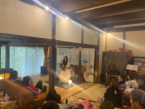 a woman standing on a stage in front of a crowd at Kizuna Guesthouse in Kizugawa