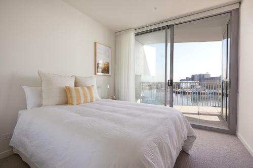 a bedroom with a white bed and a large window at Talle by Follo in Newcastle