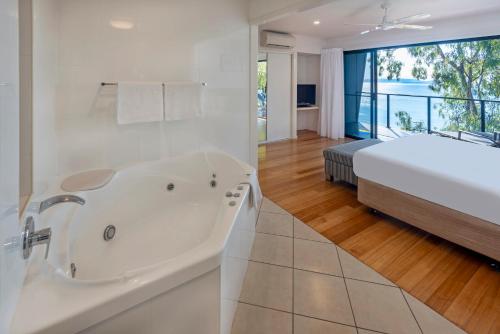 a white bathroom with a tub and a bed at Shorelines in Hamilton Island