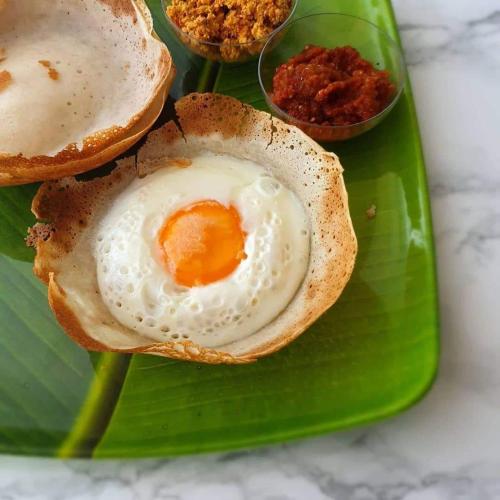 a fried egg in a bun on a green plate at Nilaveli Guest House in Nilaveli