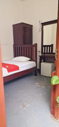 a bedroom with a wooden bed and a mirror at Station Garden Hotel And Resturant in Jaffna