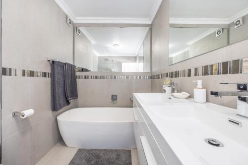 ein weißes Badezimmer mit einer Badewanne und einem Waschbecken in der Unterkunft Oceanview Holiday Accommodation in Bloubergstrand