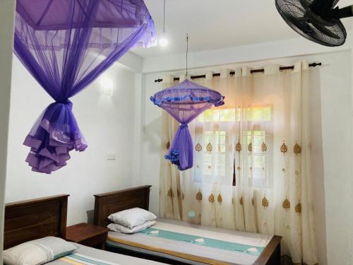 two purple umbrellas are hanging in a room at Sujeewa Holiday Resort Anuradhapura in Anuradhapura