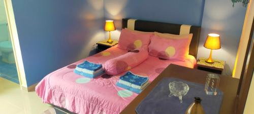 a bedroom with a pink bed with two lamps at Relaxing Retreats at Cocobay Apartments in Port Dickson