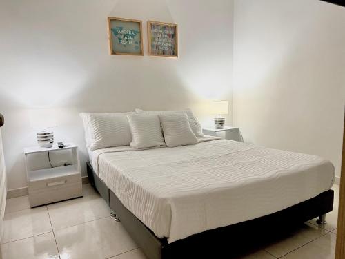 a bedroom with a bed with white sheets and pillows at Moderno Apartamento Valle del Lili in Cali