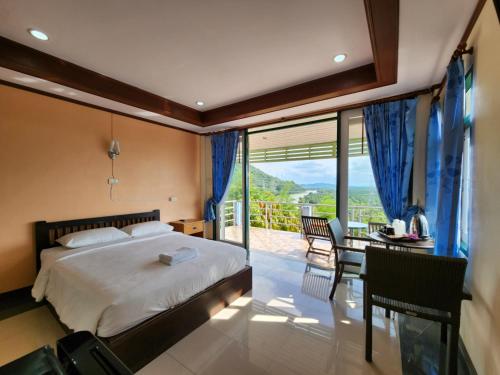 a bedroom with a bed and a table and a balcony at Baan Khao Noi Resort in Suratthani