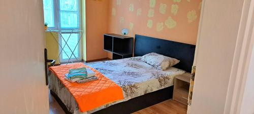 - une petite chambre avec un lit et une couverture orange dans l'établissement ALANA Apartment, à Stara Zagora
