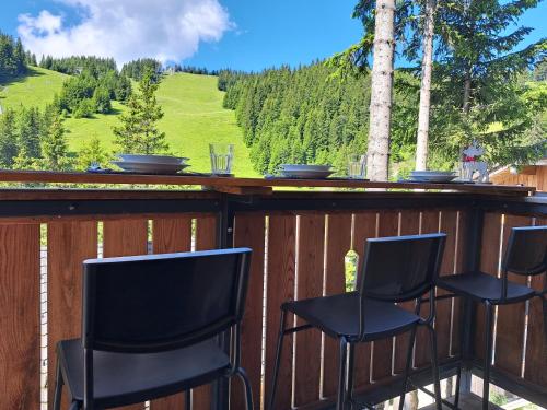 a bar with four chairs on a deck with a view at Golte SkiCenter Apartment in Mozirje