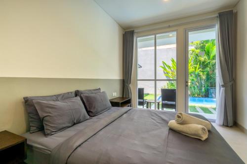 a bedroom with a large bed with a large window at Sapo Jimbaran Bali in Ungasan