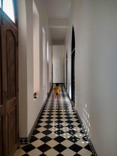 a child walking down a hallway with a black and white checkered floor at Boutique Homestay With Art Center in Courtyard House in Udaipur