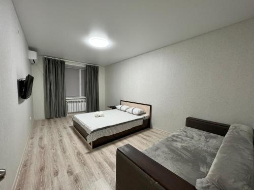 um quarto com uma cama e um sofá em Уютная и новая квартира в Костанае em Qostanay