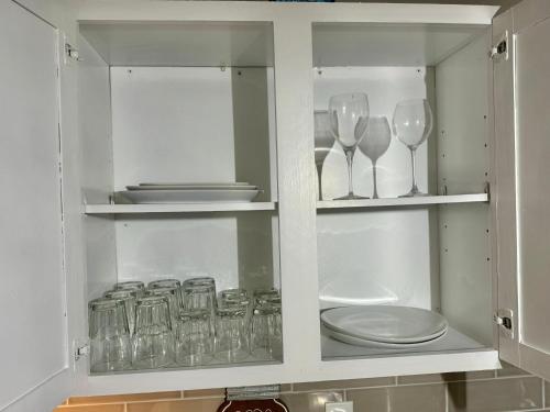 un armadietto bianco con bicchieri, piatti e stoviglie di DreamStay a Dacula