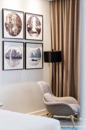 a room with a chair and pictures on the wall at Hotel Soleil Ha Long, Trademark Collection by Wyndham in Ha Long