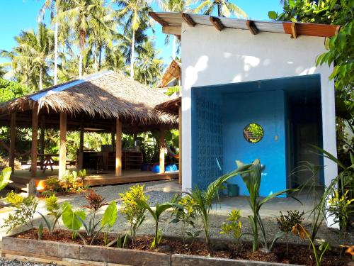 a building with a blue door and a thatch roof at Three Little Birds Hostel in General Luna