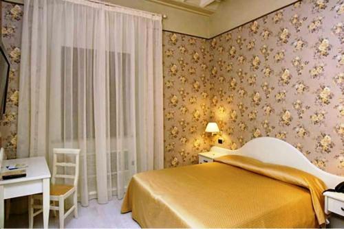 a bedroom with a bed and a desk and a window at Palazzo Riario in Viterbo