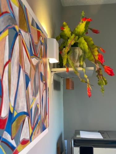 a vase of flowers on a wall with a painting at ASURE Ambassador Motor Lodge in Oamaru