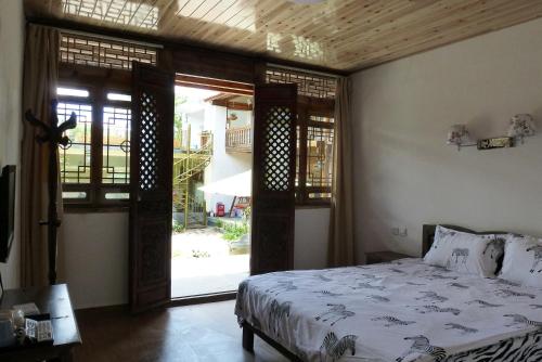 a bedroom with a bed and an open door at Tourist Courtyard Hotel in Jianchuan