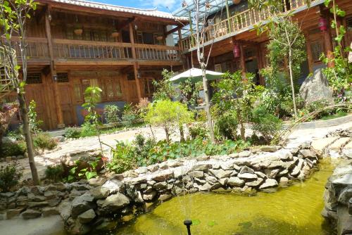 a garden with a pond in front of a building at Tourist Courtyard Hotel in Jianchuan
