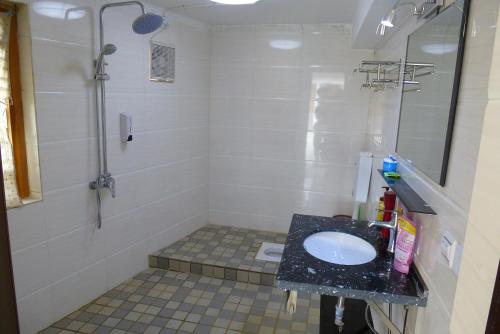 a bathroom with a sink and a shower at Tourist Courtyard Hotel in Jianchuan