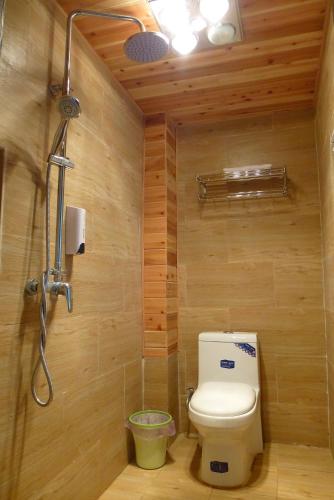 a bathroom with a toilet and a shower at Tourist Courtyard Hotel in Jianchuan