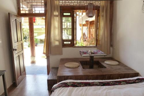 a room with a wooden table with a window at Tourist Courtyard Hotel in Jianchuan