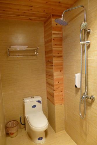 a bathroom with a toilet and a shower at Tourist Courtyard Hotel in Jianchuan