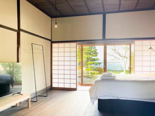 een slaapkamer met een bed en een groot raam bij Akizuki Kayabuki Kominka in Asakura